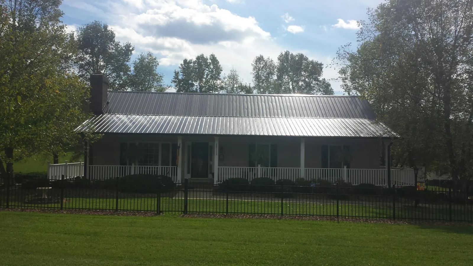 Gray metal roof on a brick ranch with a full width front porch — Gutter Guard Installation work by our crew in Ogden